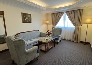 A hotel room with a sofa, armchairs, a coffee table, and a lamp. - Taj Celine Hotel (Jeddah)