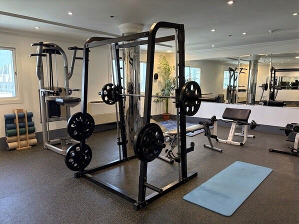 A gym with weightlifting equipment, a bench, and a mat. - Taj Celine Hotel (Jeddah)