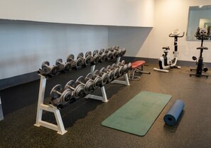 A gym with weightlifting equipment, exercise machines, and a yoga mat. - Taj Celine Hotel (Jeddah)