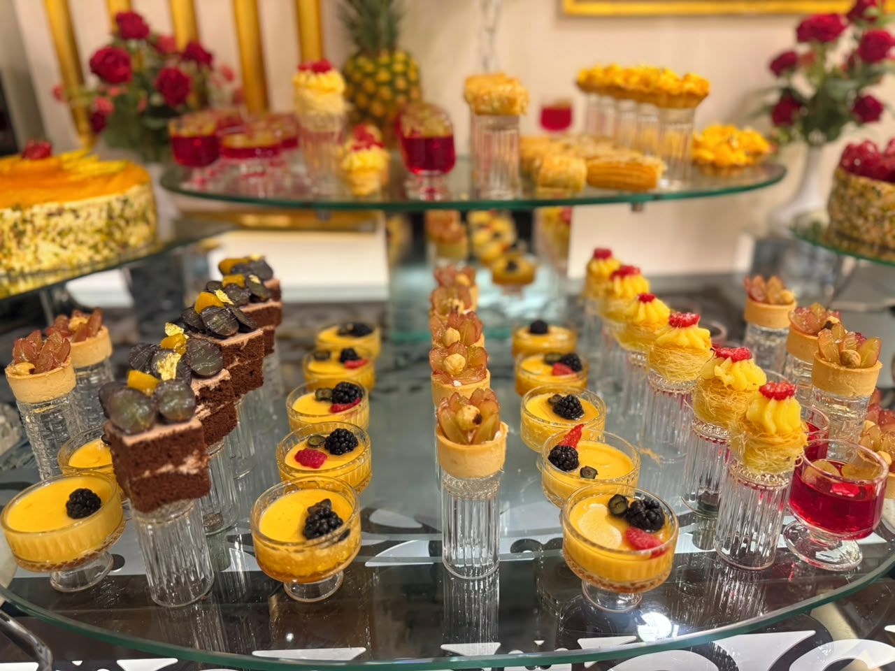 A dessert buffet with various sweet treats arranged on glass stands.