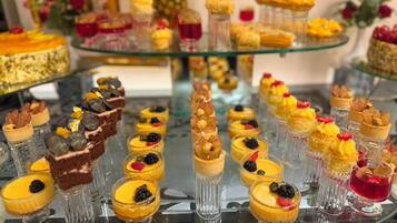 A dessert buffet with various sweet treats arranged on glass stands.