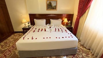 Une chambre d’hôtel avec un grand lit, deux tables de chevet et une tête de lit.