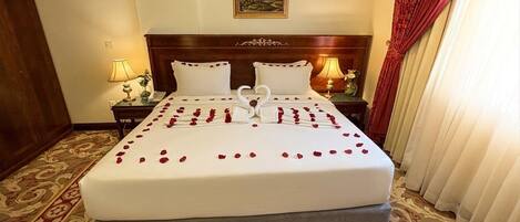 Una habitación de hotel con una cama grande, dos mesitas de noche y un cabecero.