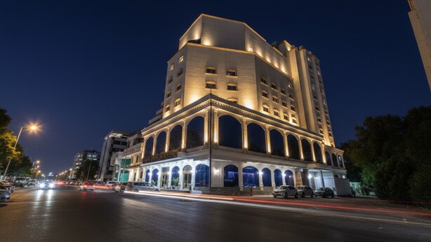 A multi-story hotel with a classic architectural design, featuring a prominent central archway and multiple balconies.