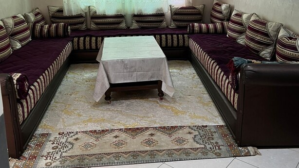 A living room with a sofa set, a coffee table, and a TV mounted on the wall. - Apartment sidi rahhal near beach (Sidi Rahal)