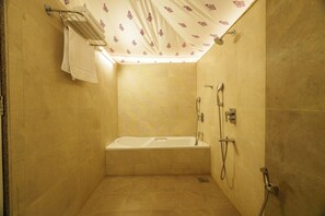 A small, well-lit bathroom with a bathtub, a shower, and a towel rack.