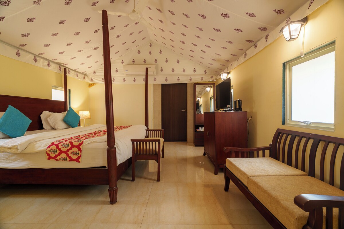 A four-poster bed with a wooden headboard, a wooden bench, and a wooden wardrobe.