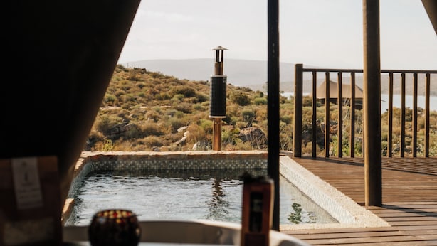 Un espace piscine offrant une vue sur un paysage vallonné, avec une terrasse en bois et une rambarde en métal.