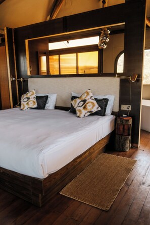 Una cama doble con estructura de madera, cabecera y mesita de noche con lámpara.