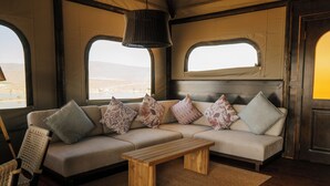 Un intérieur chaleureux avec un canapé, des coussins, un banc en bois et un luminaire suspendu.