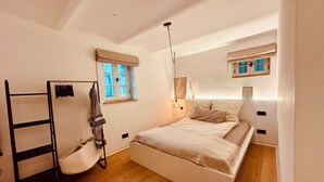 Un dormitorio con cama, ventana, lámpara colgante y armario.