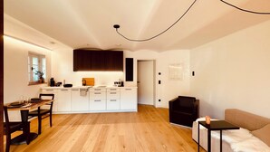 Una cocina moderna con armarios blancos, una mesa de comedor de madera y una silla negra.