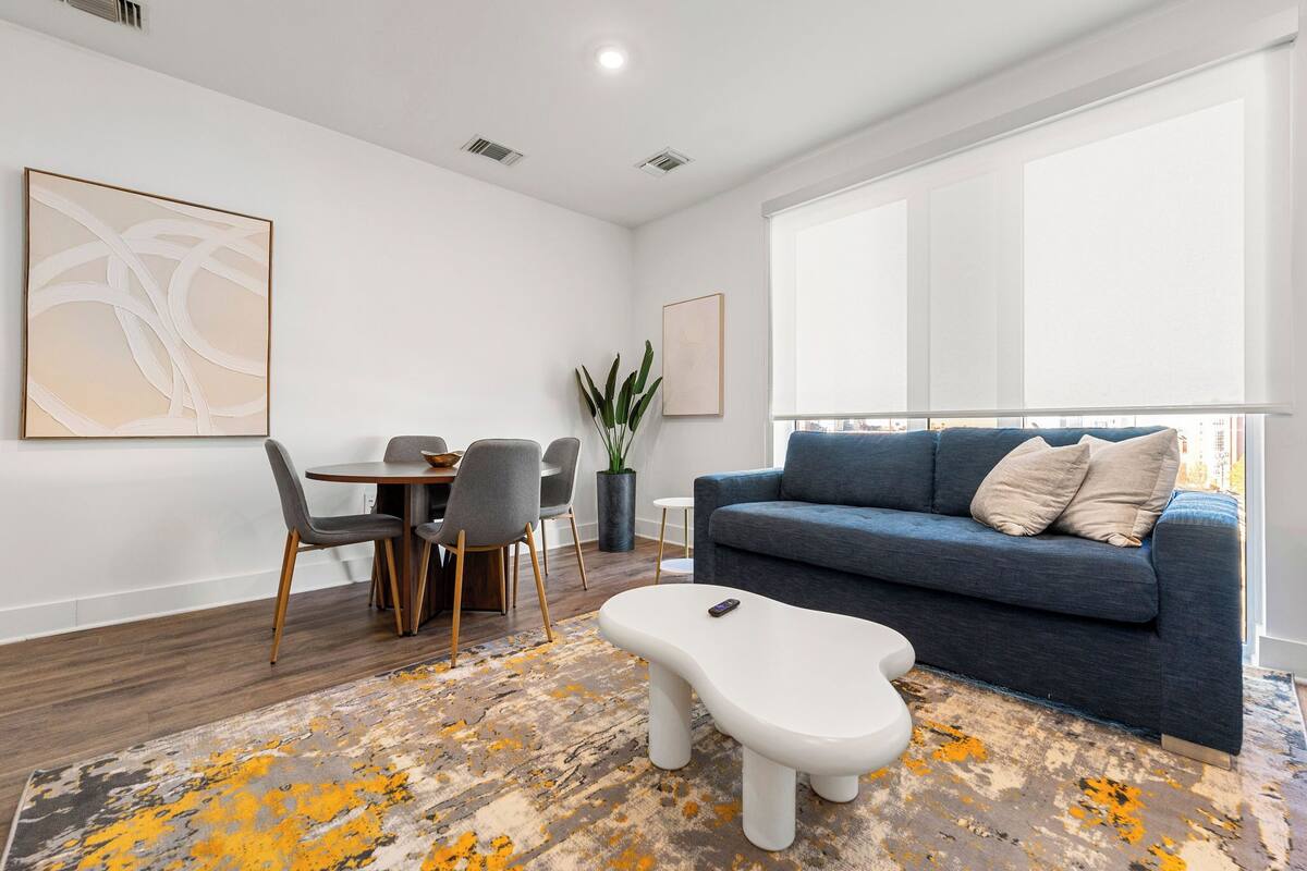 A modern living room with a sofa, coffee table, and dining area.