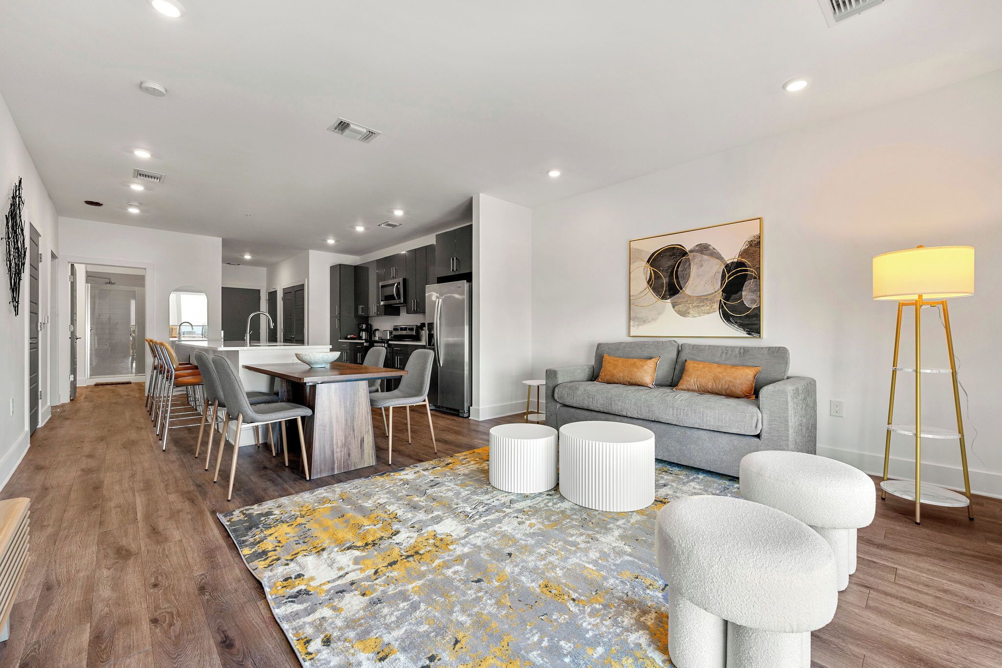 Una sala moderna con un sofá gris, una mesa de centro y un comedor con sillas y una mesa.