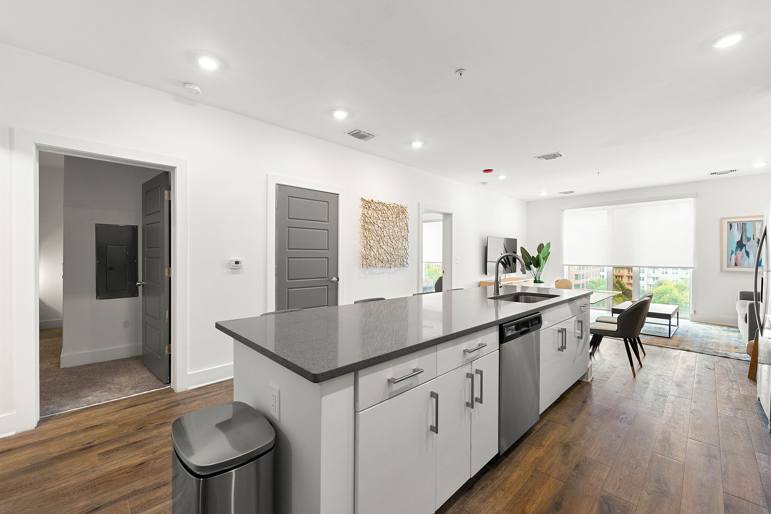 A modern kitchen with a large island, white cabinetry, and a view to the outside.