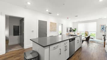 A modern kitchen with a large island, white cabinetry, and a view to the outside.