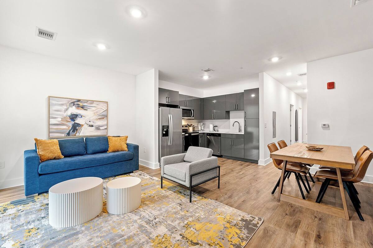 A modern apartment with a living room, dining area, and kitchen.