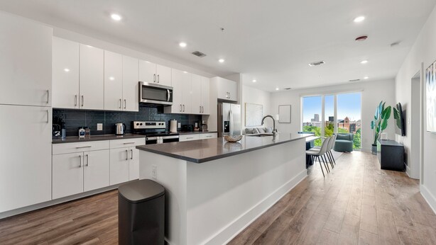 Een moderne keuken met witte kasten, een groot eiland en uitzicht op de stad.