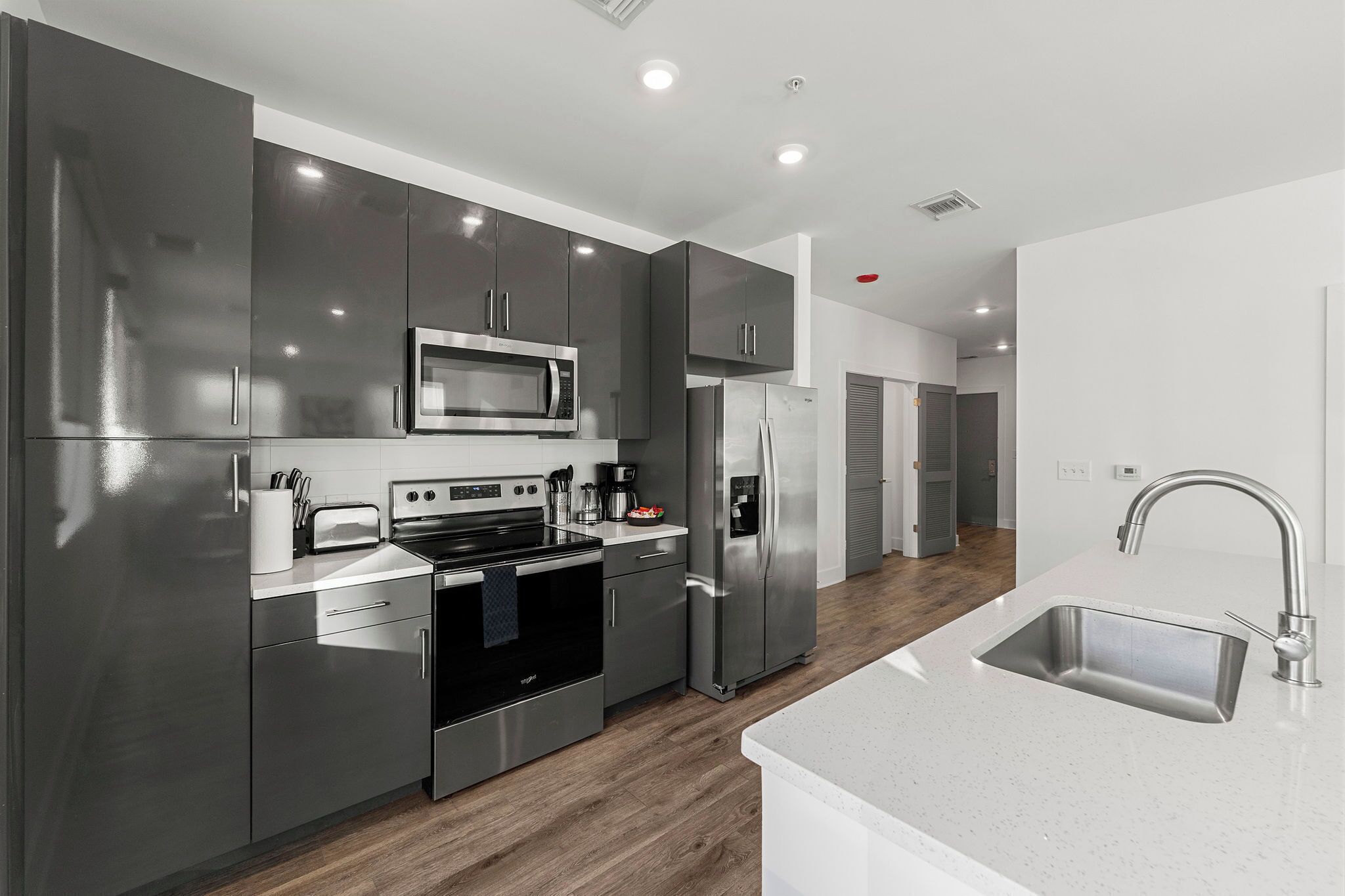 A modern kitchen with stainless steel appliances, a white countertop, and a sleek design.