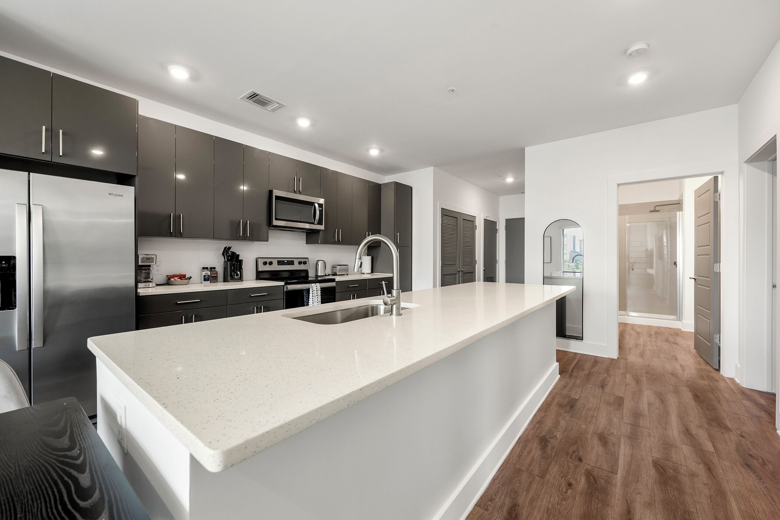 A modern kitchen with a large island, stainless steel appliances, and dark cabinetry.