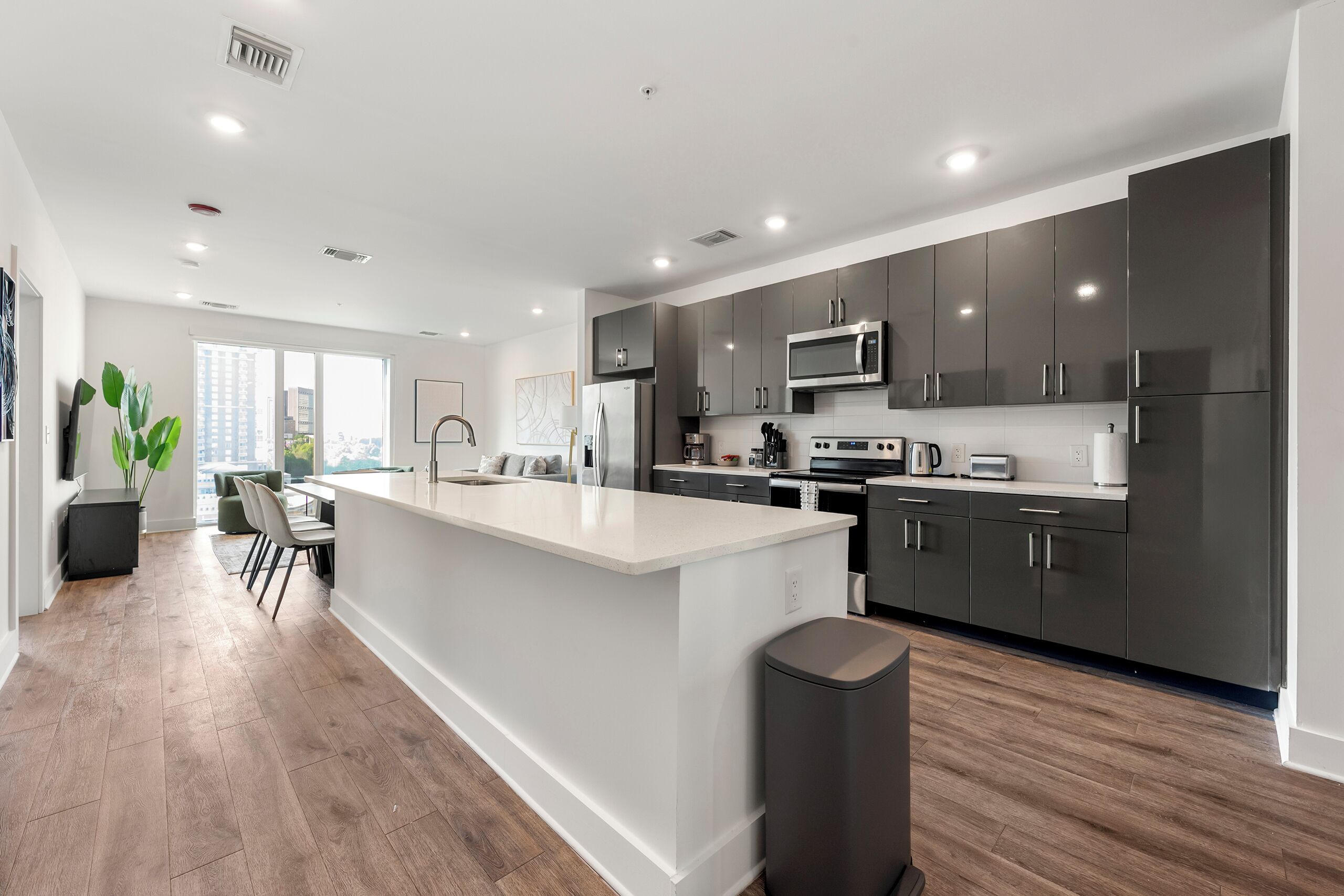 Una cucina moderna con mobili scuri, una grande isola e vista sulla città.