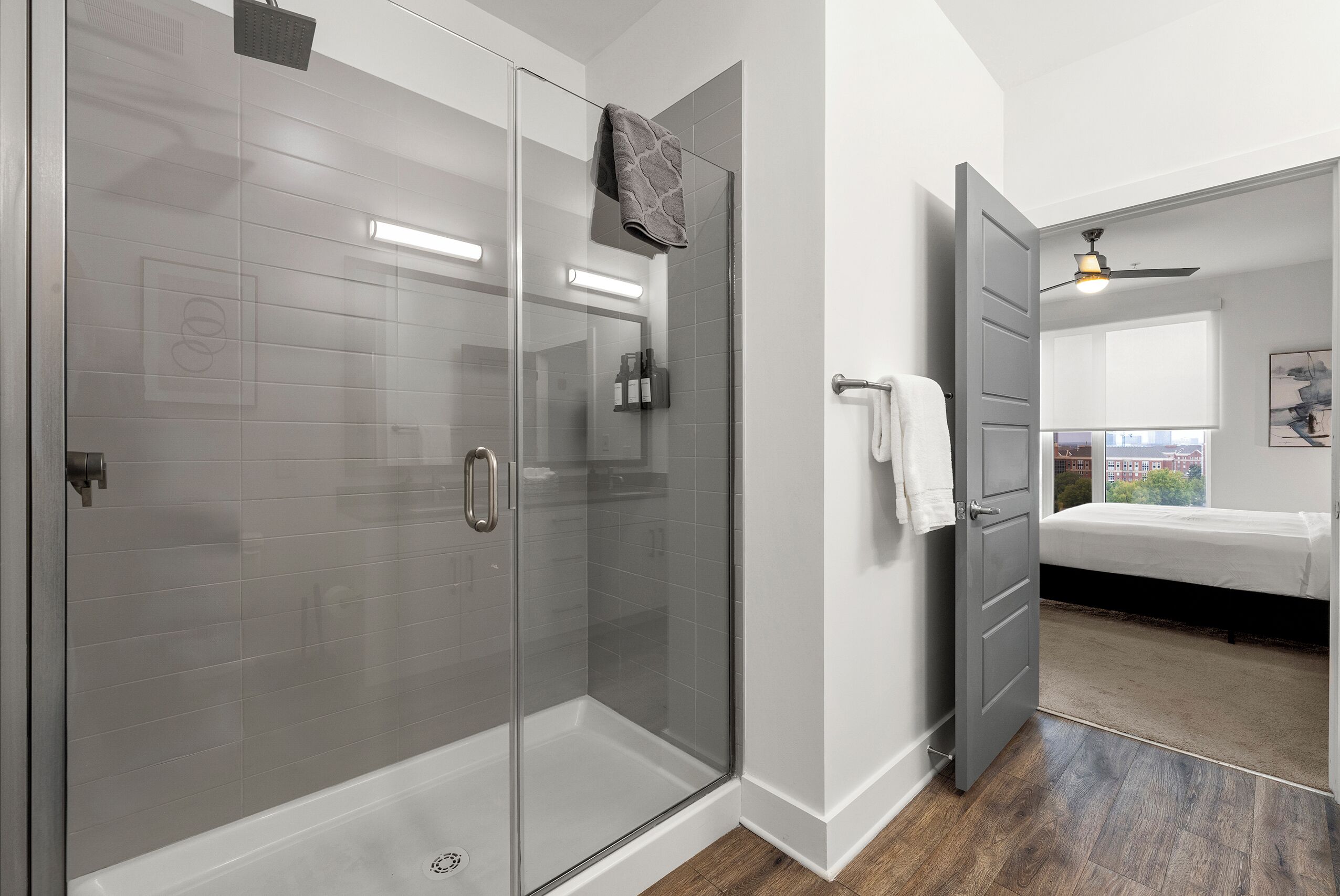 A modern bathroom with a glass shower enclosure, a white bathtub, and a visible towel rack.