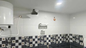 A bathroom with a white toilet, a shower, and a tiled wall with a checkered pattern.