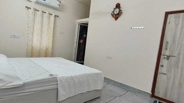 A bedroom with a bed, a wardrobe, a door, and an air conditioning unit on the wall.