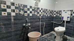 A bathroom with a checkered tile backsplash, a toilet, a bidet, and a bucket.