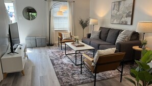 Ein modernes Wohnzimmer mit einer Couch, Sesseln, einem Couchtisch und einem Fernseher.