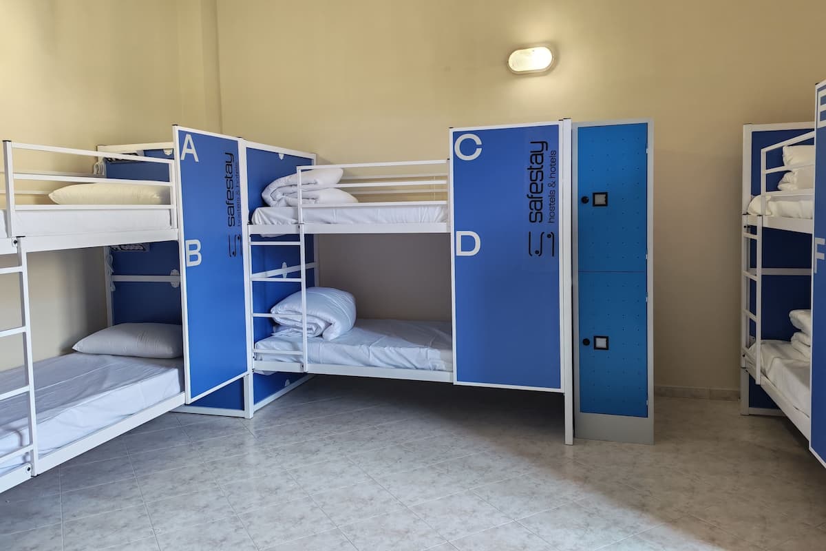 Une chambre avec des lits superposés étiquetés A, B, C et D, et une armoire bleue portant la mention « sécurité ».
