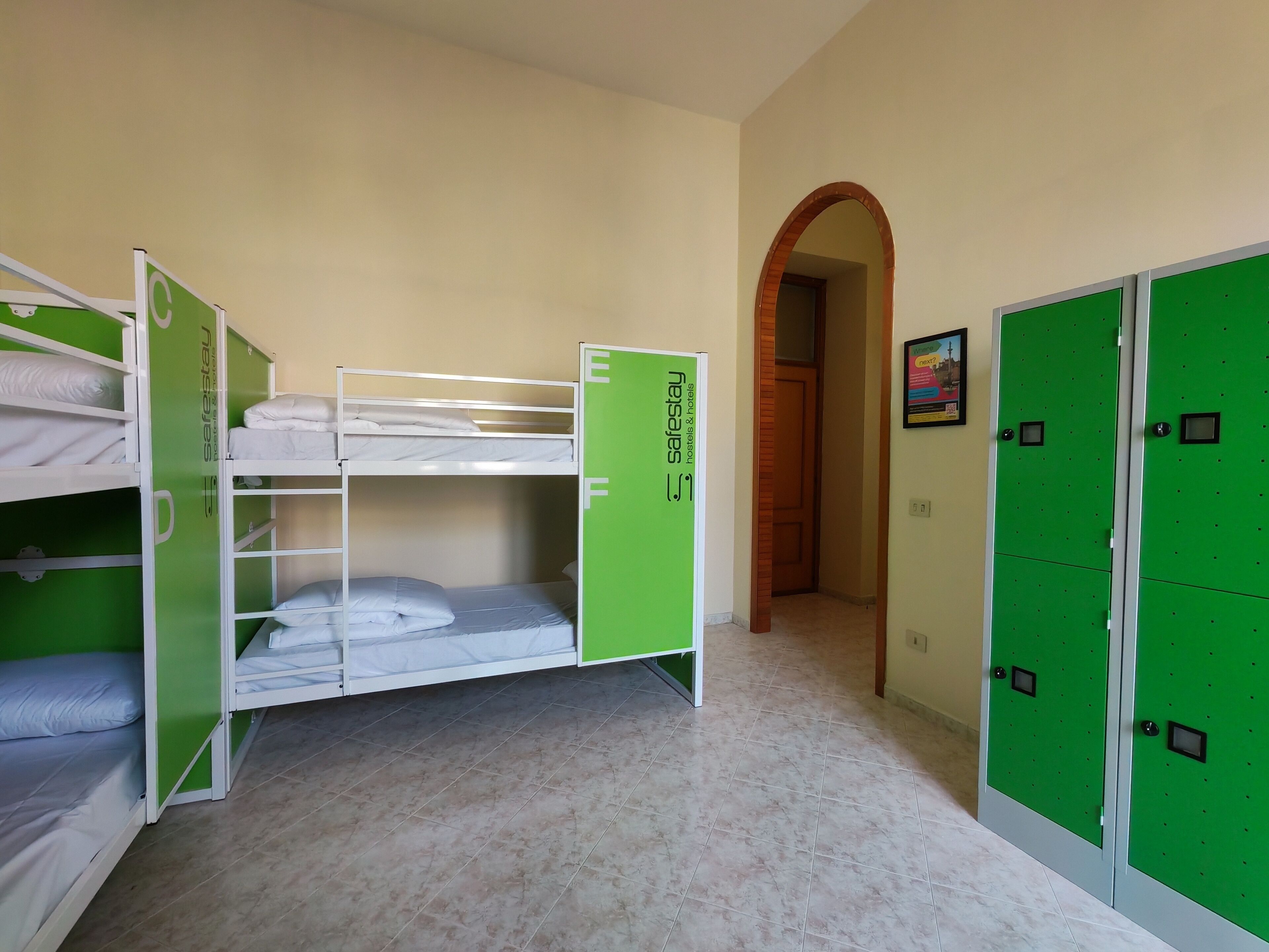 Una habitación con literas, un armario verde y una puerta que da a otra habitación.