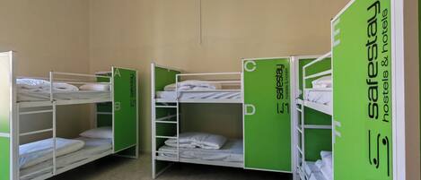 Een hostelkamer met stapelbedden, groene kasten en een hanglamp.
