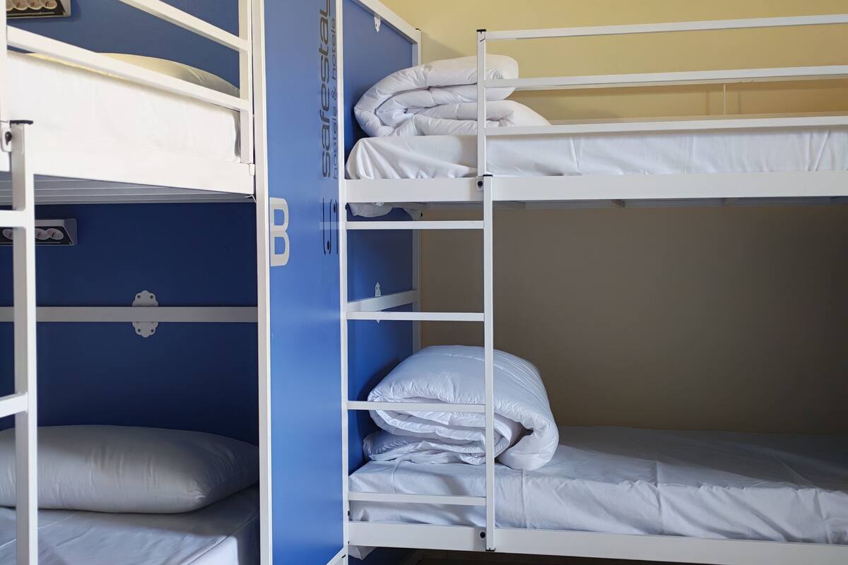 Un lit superposé avec une literie blanche et un mur bleu.