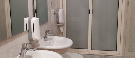 A bathroom with two sinks, a toilet, and a shower enclosure.