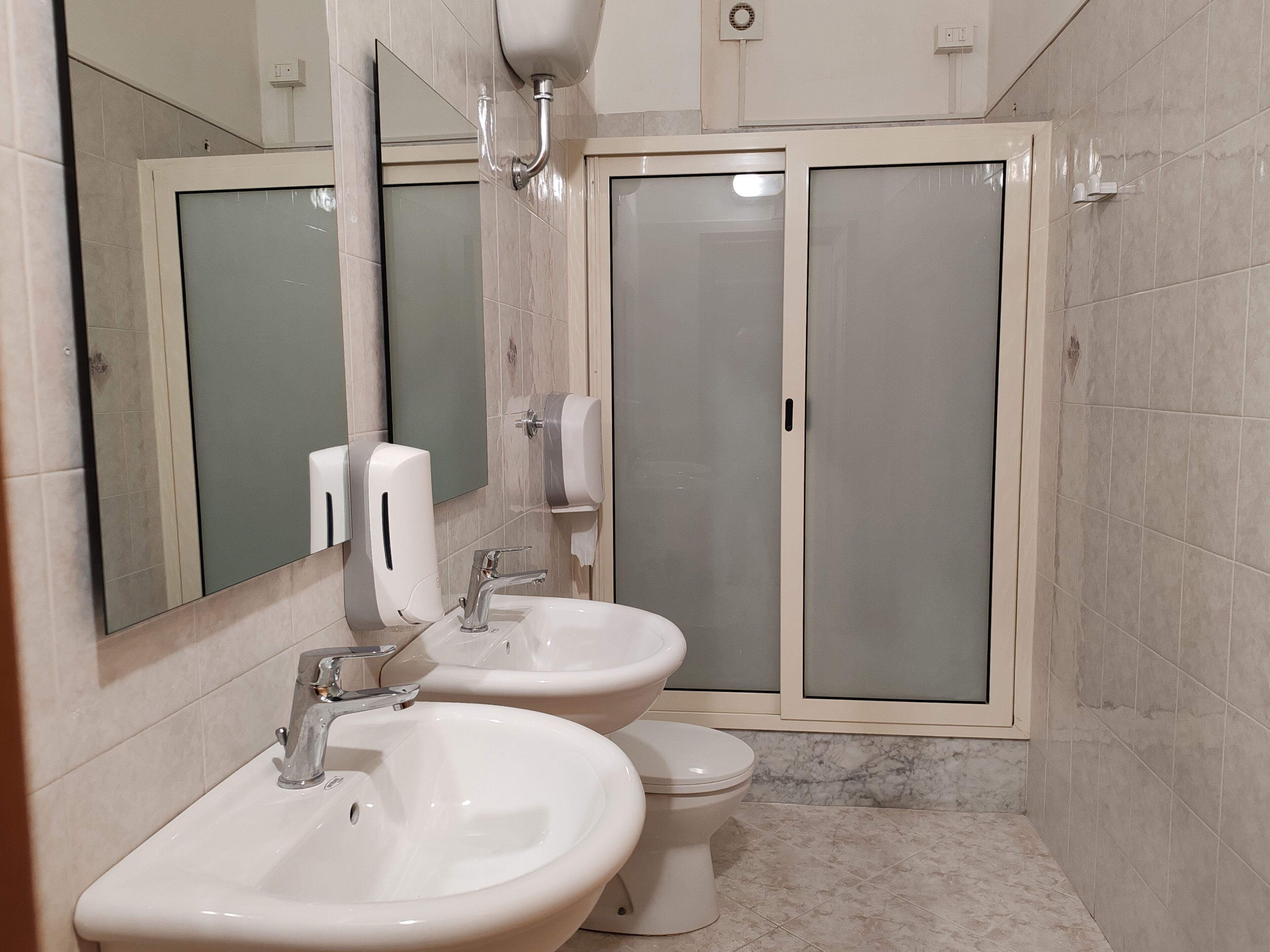 A bathroom with two sinks, a toilet, and a shower enclosure.