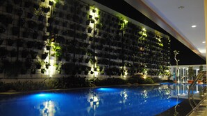 Ein Swimmingpool mit spiegelnder Oberfläche, umgeben von einer Mauer mit zahlreichen Pflanzgefäßen.