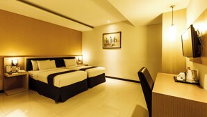 Une chambre d’hôtel comprenant un lit, des tables de chevet, un bureau, une chaise, un téléviseur et un tableau au mur.
