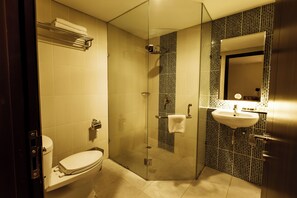 Ein modernes Badezimmer mit einer gläsernen Duschkabine, einer Toilette und einem Waschbecken mit Spiegel darüber.