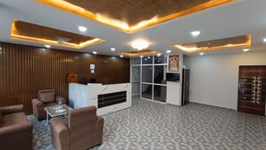A reception area with a marble reception desk, seating, and a patterned floor. - Spark Inn Hotel (Pune)