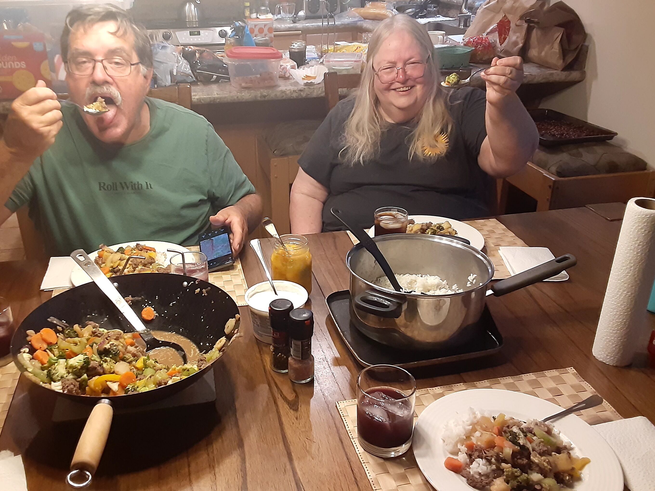 A dining table with various dishes, a smartphone, and a pot of rice.
