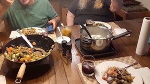 Un tavolo da pranzo con diversi piatti, uno smartphone e una pentola di riso.