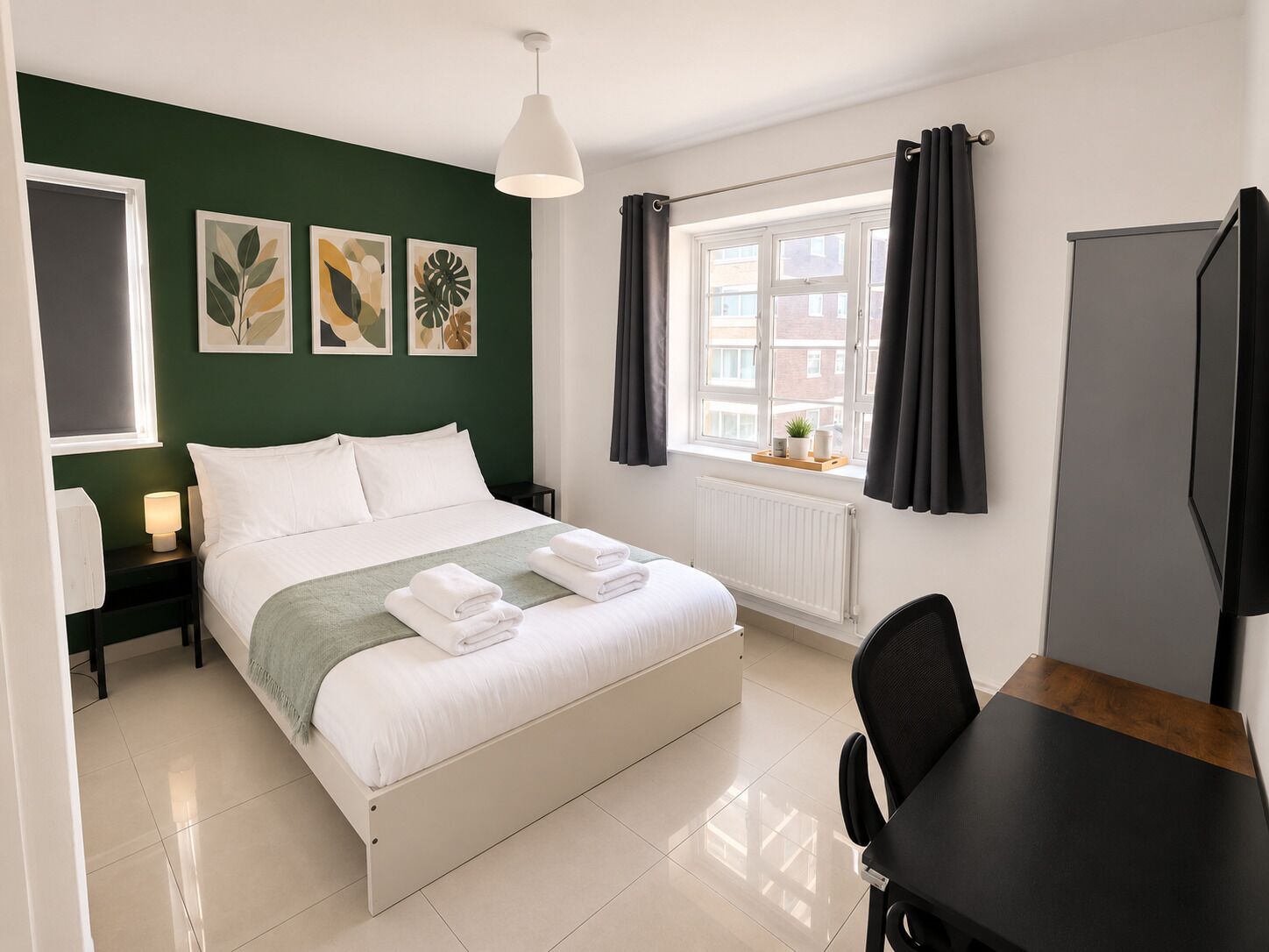 Habitación de hotel con cama, escritorio, silla, ventana con cortinas y una obra de arte en la pared.
