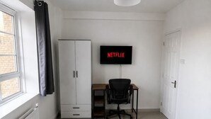 Een hotelkamer met een bed, een bureau, een stoel, een televisietoestel en een raam.