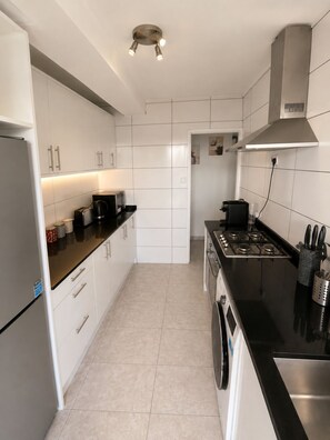 A modern kitchen with white cabinets, a black countertop, a stainless steel range, and a built-in oven. - Spacious 3BR/2BA – Central London - Walk to Paddington / Hyde Park (London)