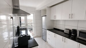 Een moderne keuken met witte kastjes, een zwart aanrecht, roestvrijstalen apparatuur en een raam met uitzicht.