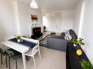 A modern living room with a dining area, a fireplace, a television, and a sofa. - Spacious 3BR/2BA – Central London - Walk to Paddington / Hyde Park (London)