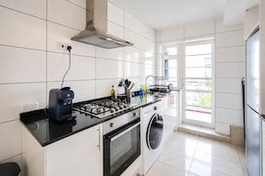 Une cuisine moderne équipée d’une cuisinière à gaz, d’un four et d’un lave-linge encastré.