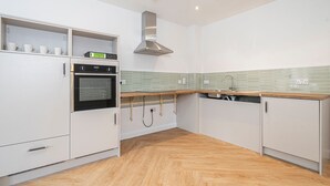 A modern kitchen with white cabinets, a built-in oven, and a stainless steel range hood. - Quiet Luxe Escape 65s Only (Leatherhead)