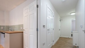 A modern kitchen with white cabinetry, a wooden countertop, and a green backsplash. - Quiet Luxe Escape 65s Only (Leatherhead)
